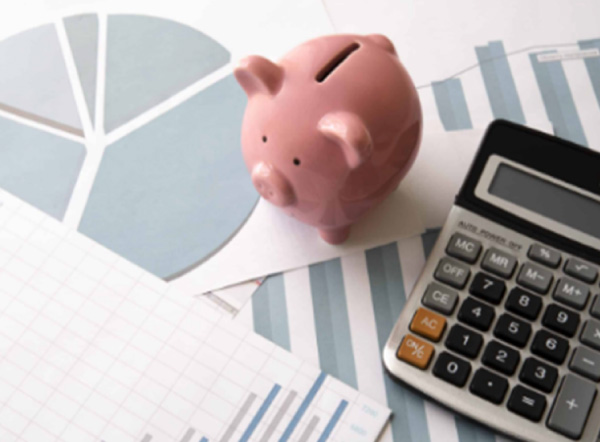 Pink piggy bank and calculator on financial charts
